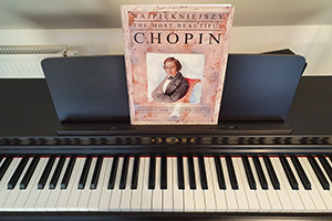 Pianino a na nim zbiór nut Szopena. Na zbiorze jego portret